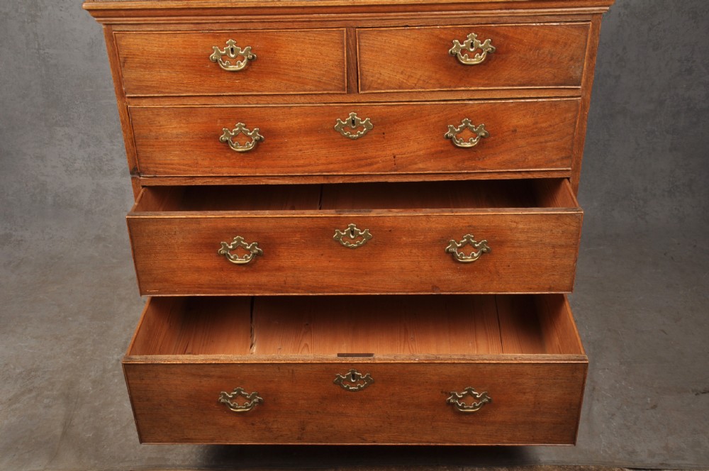 An 18th-century Georgian oak chest of drawers featuring two short drawers over three long drawers with brass drop handles and bracket feet. View VII