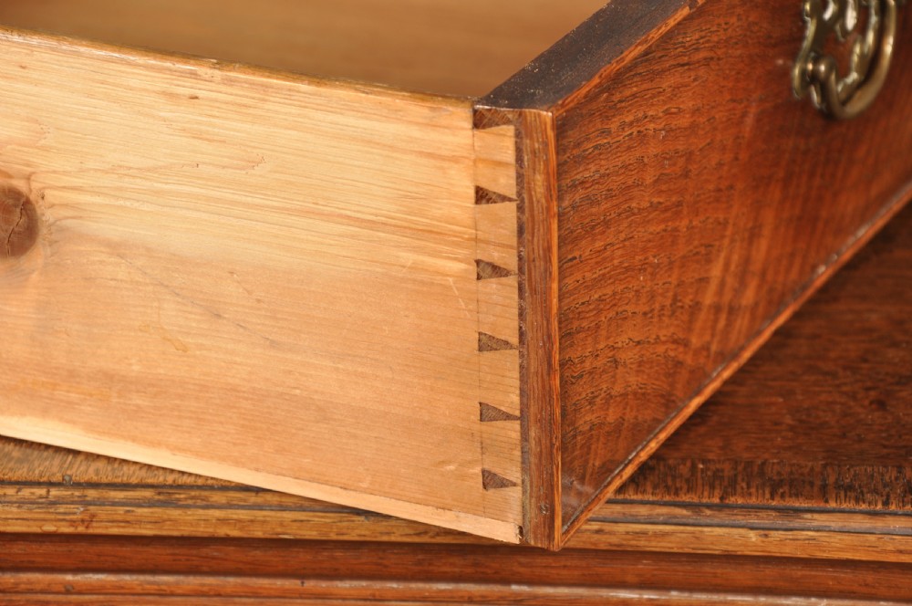 An 18th-century Georgian oak chest of drawers featuring two short drawers over three long drawers with brass drop handles and bracket feet. View VIII