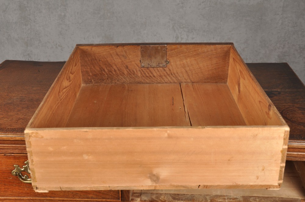 An 18th-century Georgian oak chest of drawers featuring two short drawers over three long drawers with brass drop handles and bracket feet. View IX