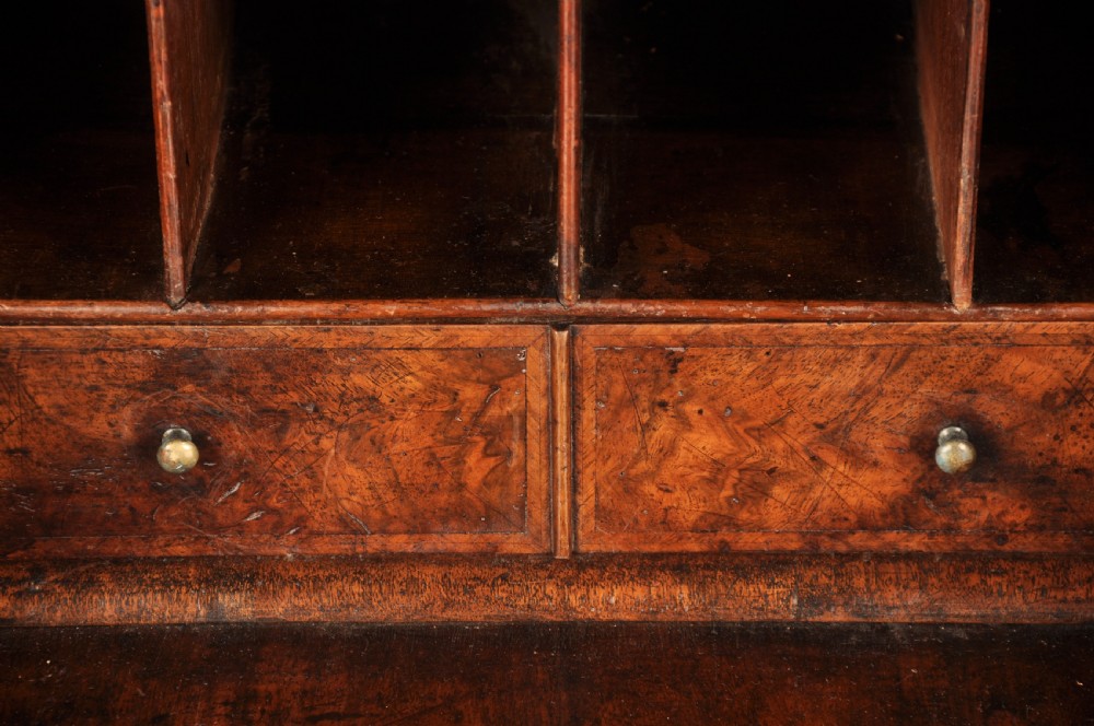An early eighteenth-century burr walnut bureau featuring a sloped fall-front writing flap above four graduated drawers with brass drop handles and bracket feet. View VII