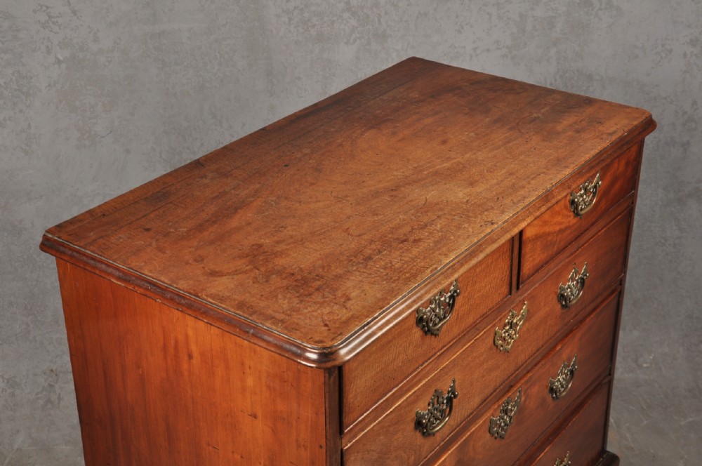 An 18th-century Georgian mahogany chest of drawers featuring two short over three long drawers with brass hardware and bracket feet. View V