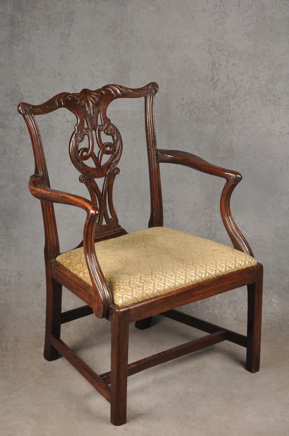 An 18th-century Chippendale mahogany open armchair featuring a carved pierced back splat, outswept arms, and a patterned fabric seat.