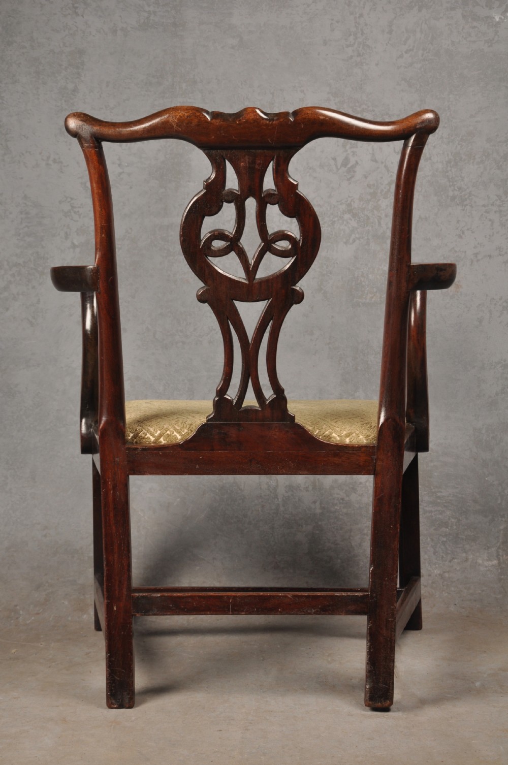 An 18th-century Chippendale mahogany open armchair featuring a carved pierced back splat, outswept arms, and a patterned fabric seat. View X