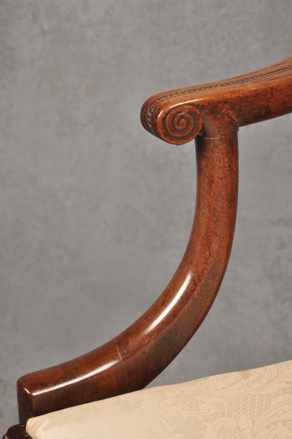 An 18th-century Chippendale mahogany armchair with a carved pierced back splat, curved arms, and a cream upholstered seat. View VI