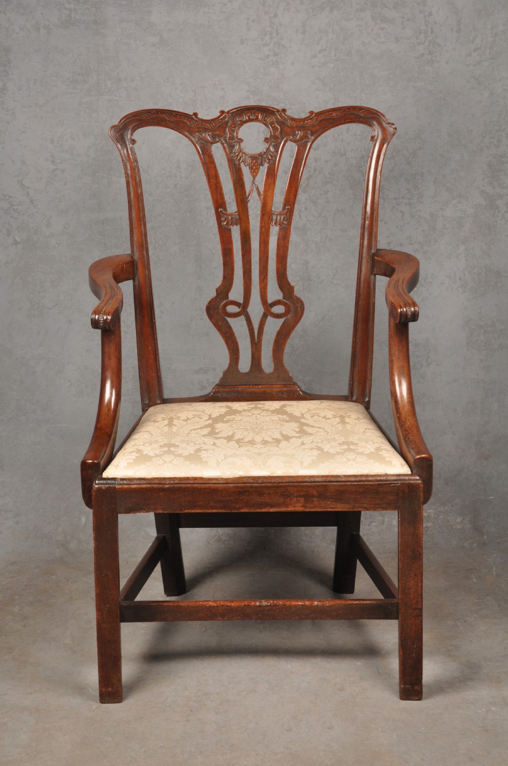 An 18th-century Chippendale mahogany armchair with a carved pierced back splat, curved arms, and a cream upholstered seat. View IX