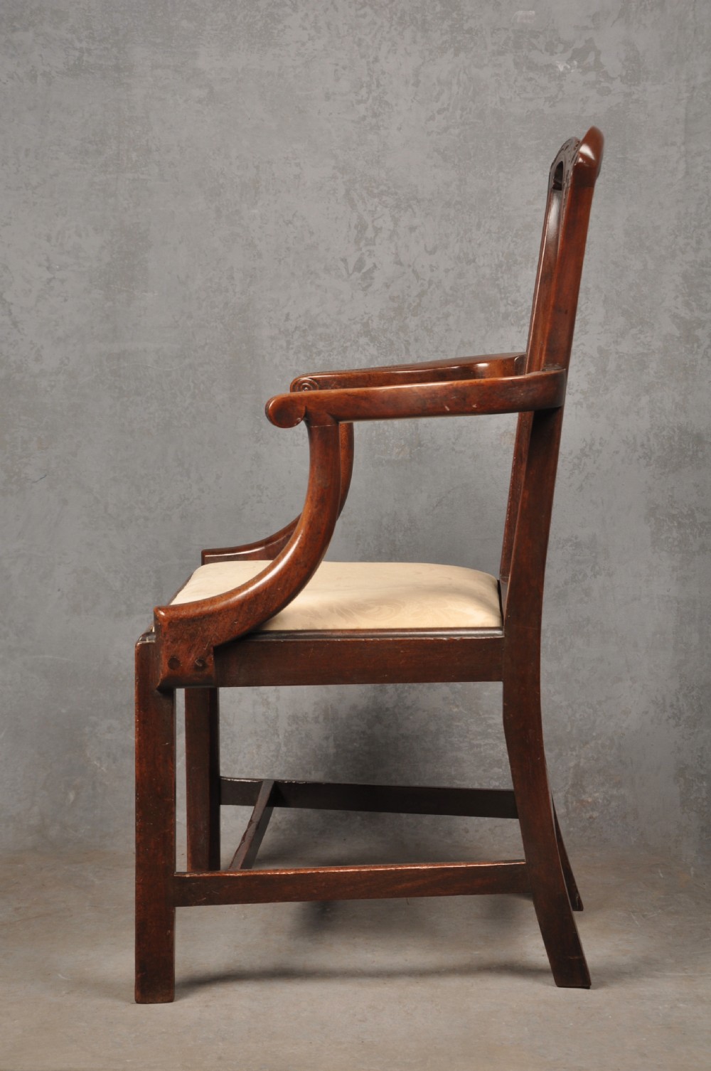An 18th-century Chippendale mahogany armchair with a carved pierced back splat, curved arms, and a cream upholstered seat. View XI