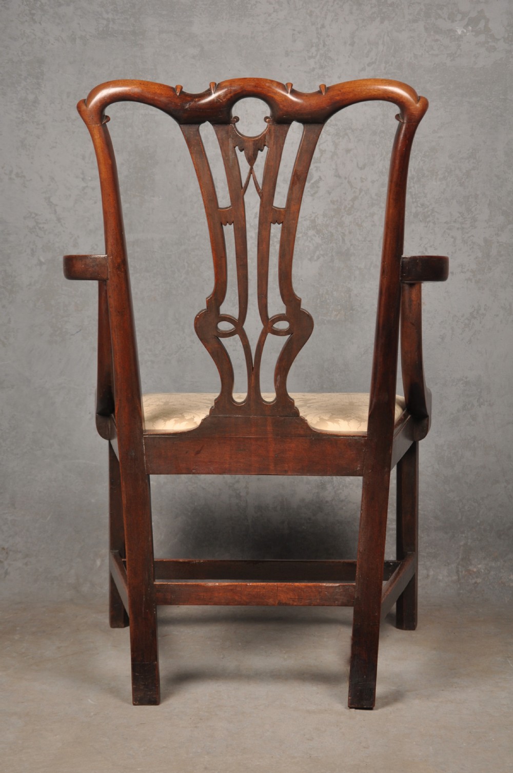 An 18th-century Chippendale mahogany armchair with a carved pierced back splat, curved arms, and a cream upholstered seat. View XII