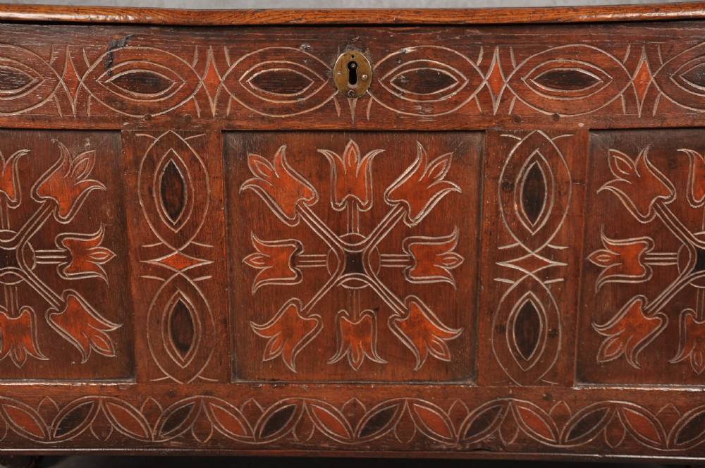 A 17th-century dark stained oak coffer with carved tulip panels and geometric border details. View V