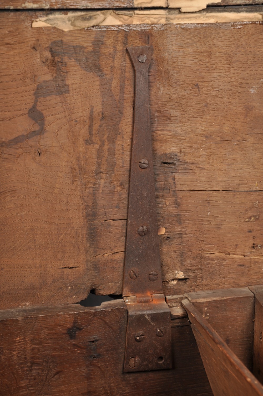 A 17th-century dark stained oak coffer with carved tulip panels and geometric border details. View IX