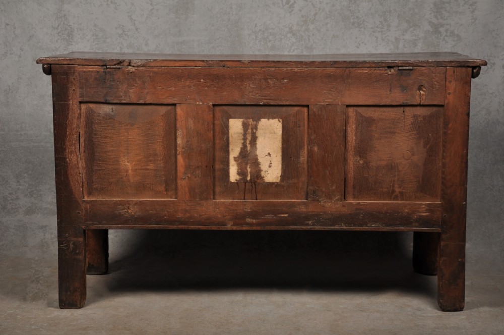 A 17th-century dark stained oak coffer with carved tulip panels and geometric border details. View XI