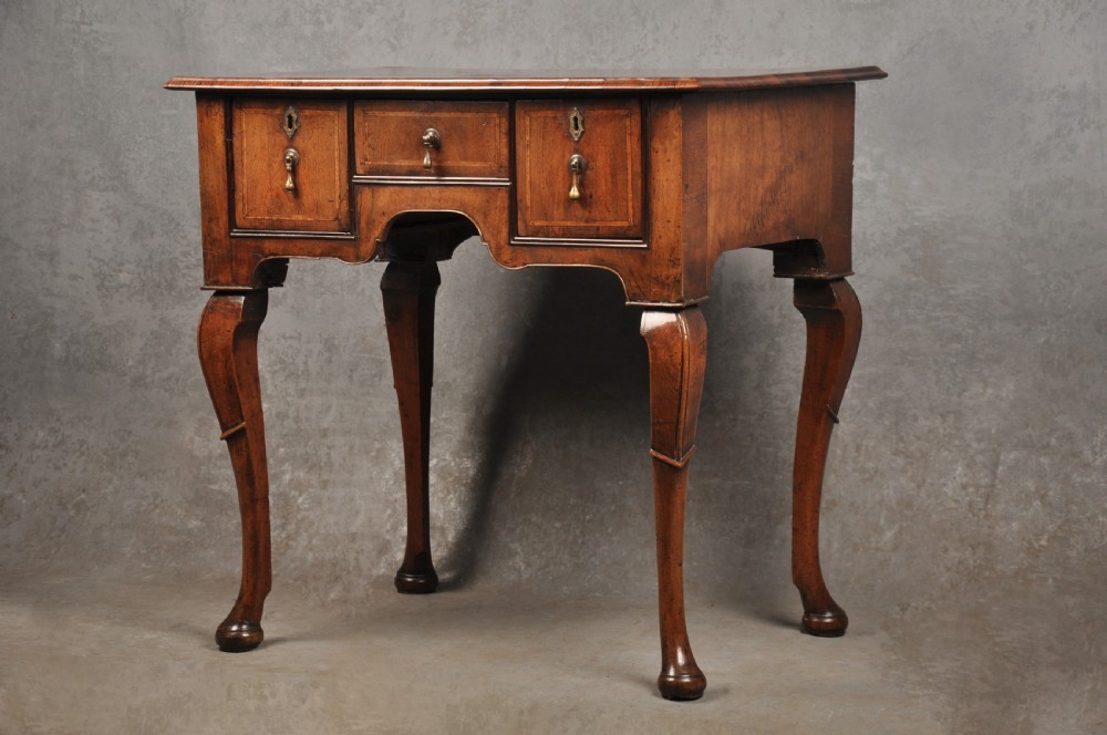 An 18th-century walnut lowboy table featuring three drawers with brass drop handles, a shaped lower apron, and cabriole legs. View III