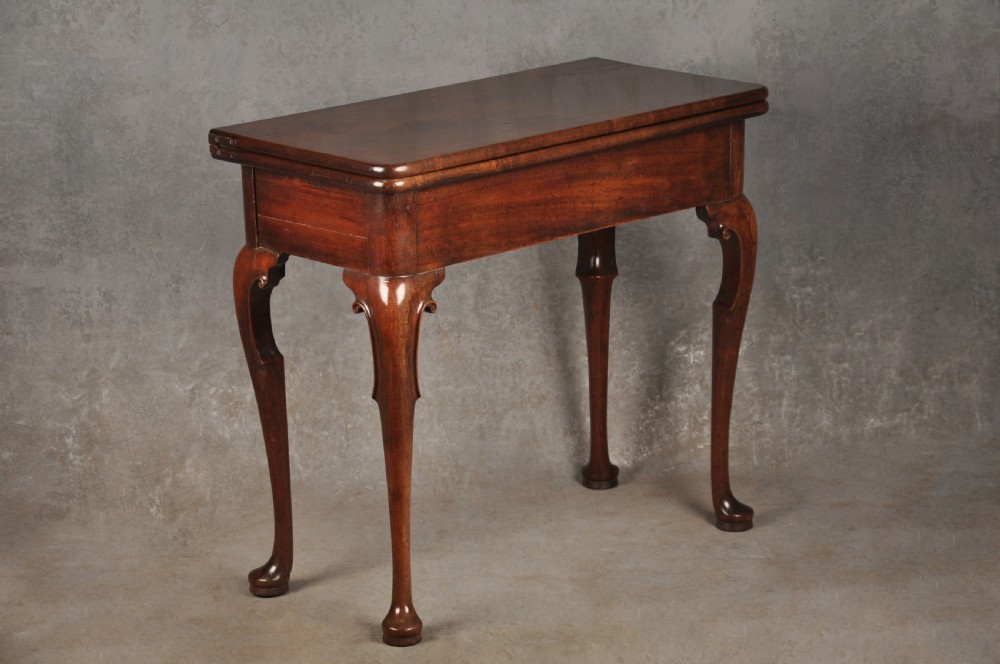 An 18th-century mahogany tea table featuring a folding rectangular top, concertina frame action, and cabriole legs with pad feet.