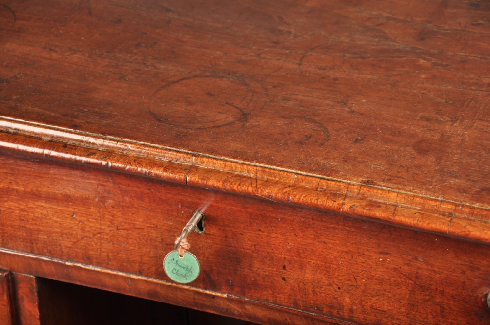 A mid-18th-century mahogany kneehole desk featuring a long upper drawer, six small side drawers, brass handles, and a central recessed cupboard on bracket feet. View II