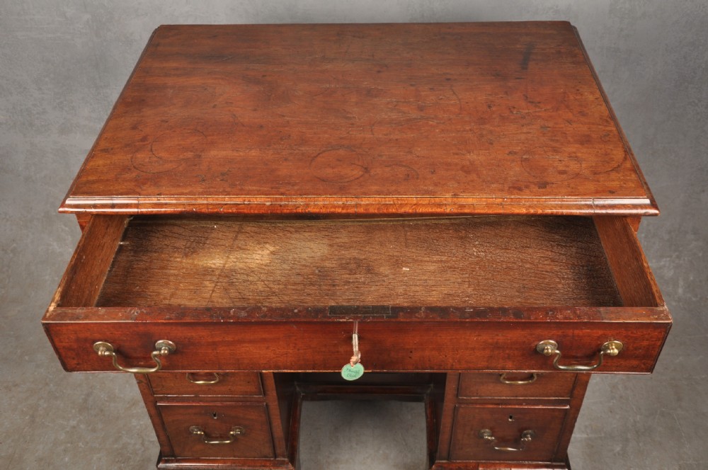 A mid-18th-century mahogany kneehole desk featuring a long upper drawer, six small side drawers, brass handles, and a central recessed cupboard on bracket feet. View III