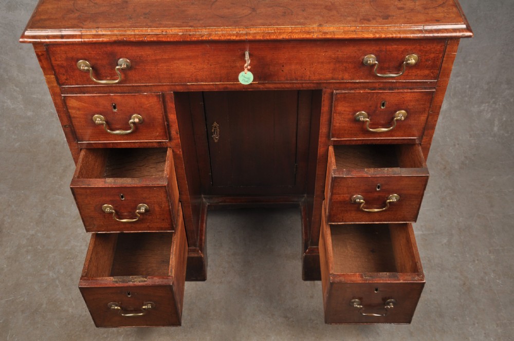 A mid-18th-century mahogany kneehole desk featuring a long upper drawer, six small side drawers, brass handles, and a central recessed cupboard on bracket feet. View IV