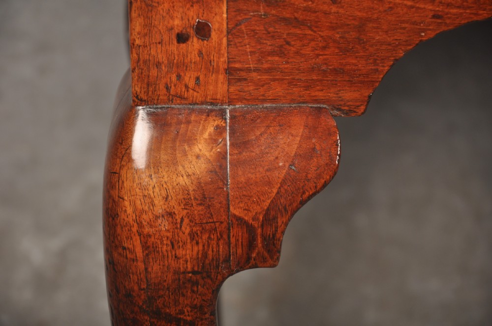 An early 18th-century red walnut lowboy table featuring three drawers with brass handles, a scalloped apron, and four cabriole legs on pad feet. View II