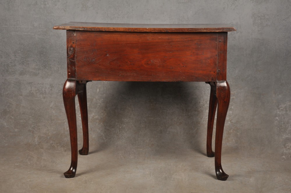 An early 18th-century red walnut lowboy table featuring three drawers with brass handles, a scalloped apron, and four cabriole legs on pad feet. View XI