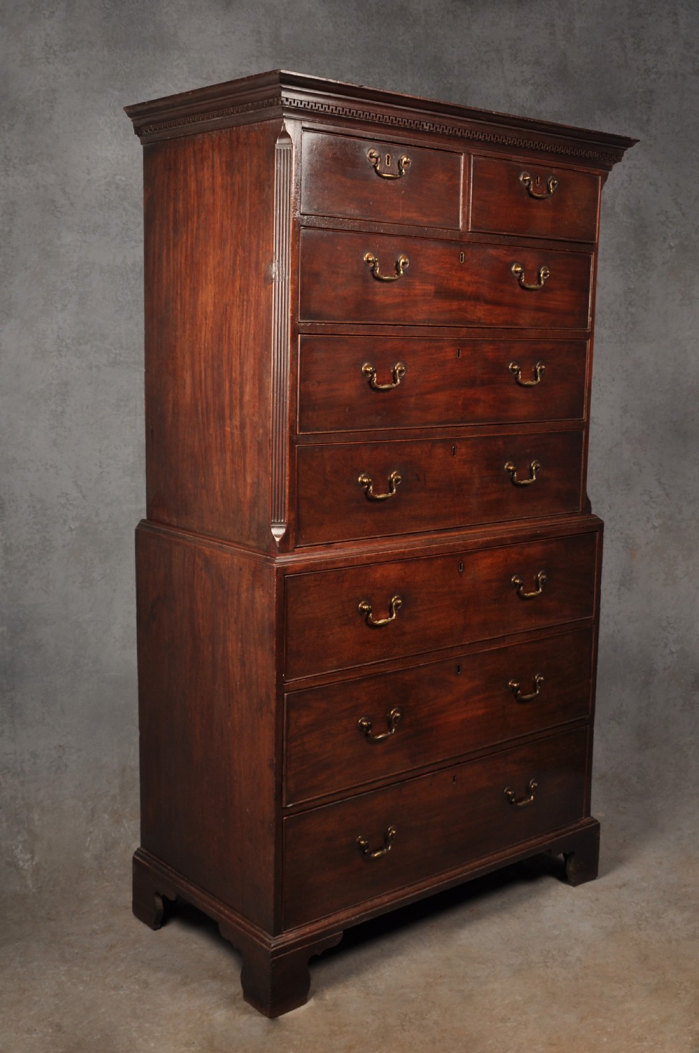 An 18th-century Georgian mahogany tallboy chest-on-chest featuring two stacked sections with brass swan-neck handles, dentil moulding, fluted canted corners, and bracket feet. View III