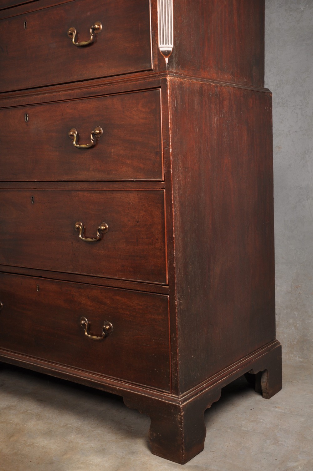 An 18th-century Georgian mahogany tallboy chest-on-chest featuring two stacked sections with brass swan-neck handles, dentil moulding, fluted canted corners, and bracket feet. View XI