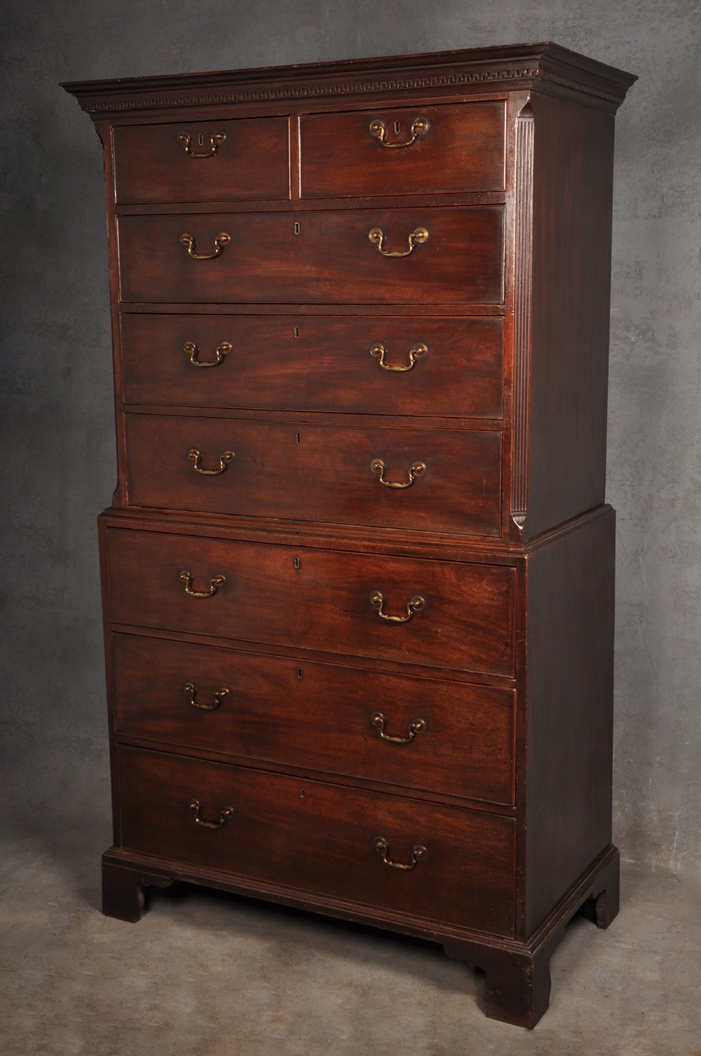 An 18th-century Georgian mahogany tallboy chest-on-chest featuring two stacked sections with brass swan-neck handles, dentil moulding, fluted canted corners, and bracket feet. View II
