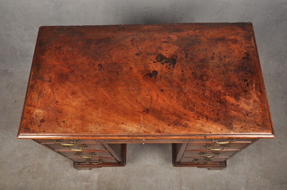 An 18th-century Georgian mahogany kneehole desk featuring brass swan-neck handles, a central recessed cupboard, and bracket feet. View IV