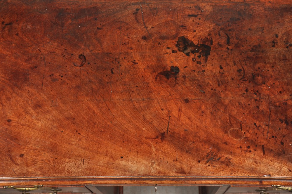An 18th-century Georgian mahogany kneehole desk featuring brass swan-neck handles, a central recessed cupboard, and bracket feet. View V