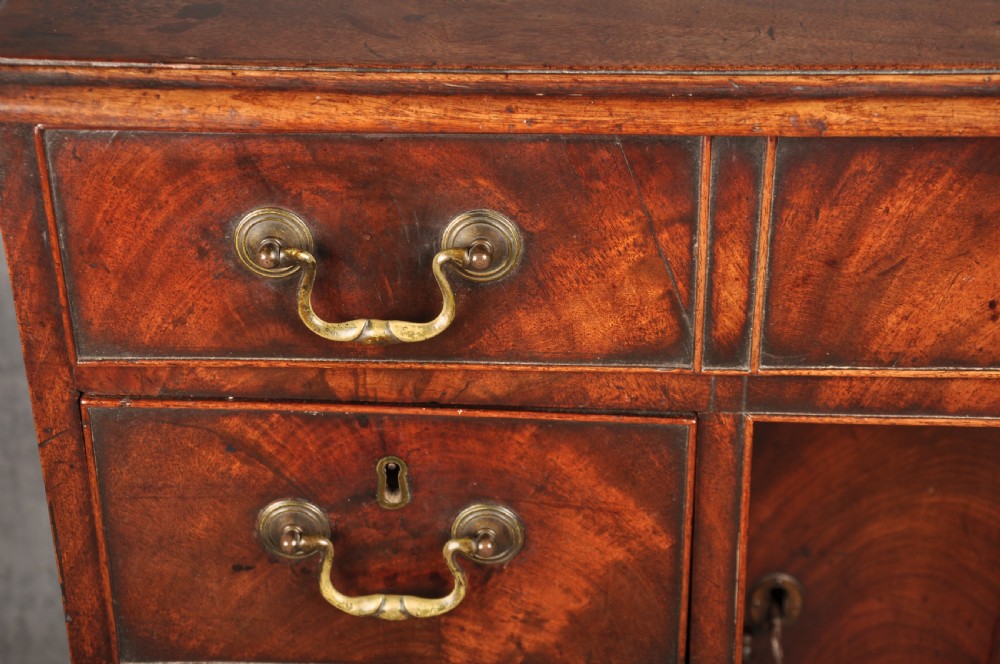An 18th-century Georgian mahogany kneehole desk featuring brass swan-neck handles, a central recessed cupboard, and bracket feet. View IX