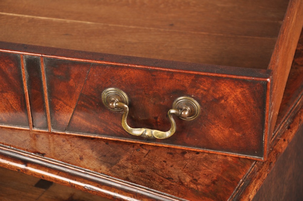 An 18th-century Georgian mahogany kneehole desk featuring brass swan-neck handles, a central recessed cupboard, and bracket feet. View X