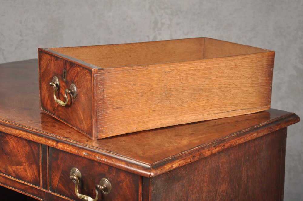 An 18th-century Georgian mahogany kneehole desk featuring brass swan-neck handles, a central recessed cupboard, and bracket feet. View XII