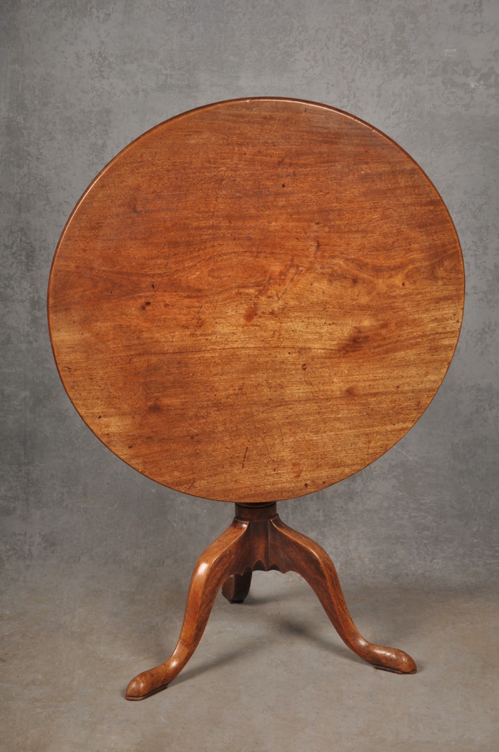 An 18th-century mahogany tripod table with a circular top supported by a turned central stem and three splayed cabriole legs with pad feet. View II