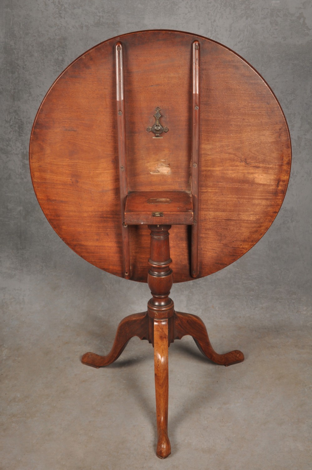 An 18th-century mahogany tripod table with a circular top supported by a turned central stem and three splayed cabriole legs with pad feet. View V