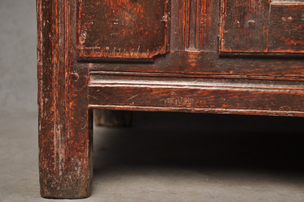 An early 18th-century dark oak dresser base featuring fielded panel cupboard doors, multiple drawers, and brass backplate handles. View IX
