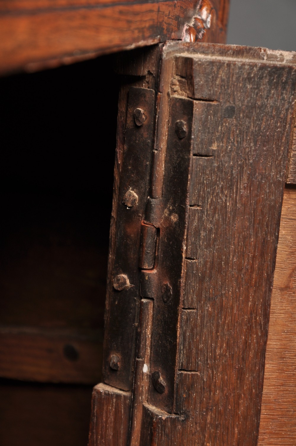 An early 18th-century dark oak dresser base featuring fielded panel cupboard doors, multiple drawers, and brass backplate handles. View XII