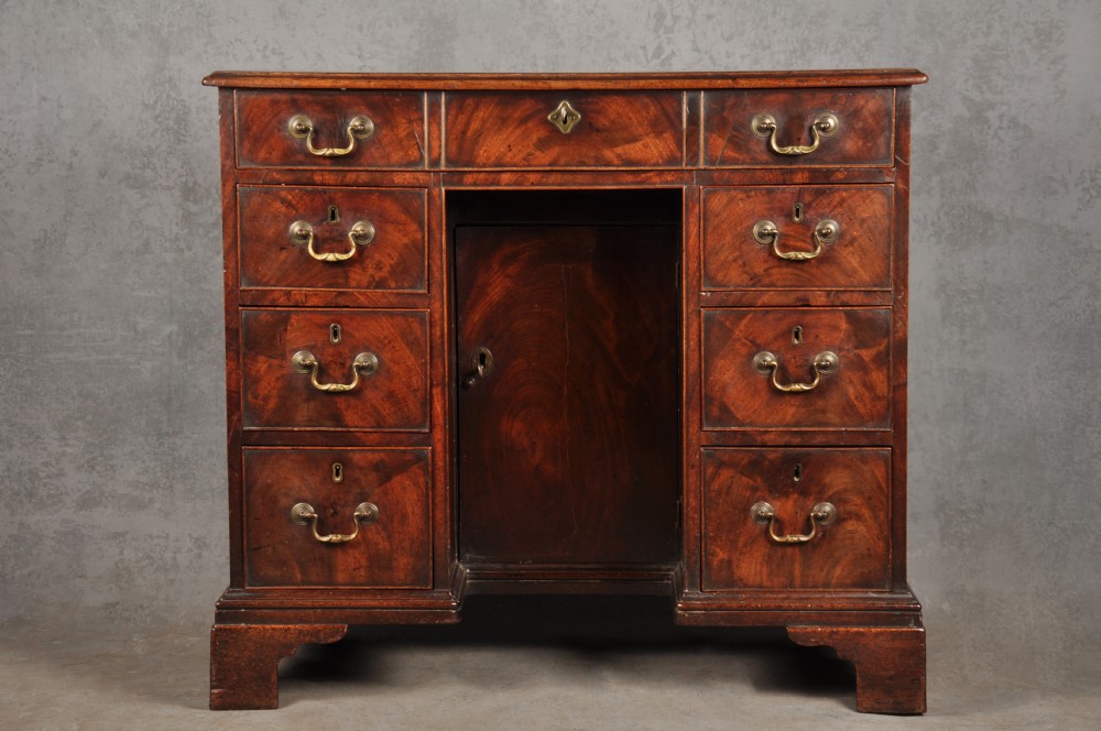 An 18th-century Georgian mahogany kneehole desk featuring brass swan-neck handles, a central recessed cupboard, and bracket feet. View XVI