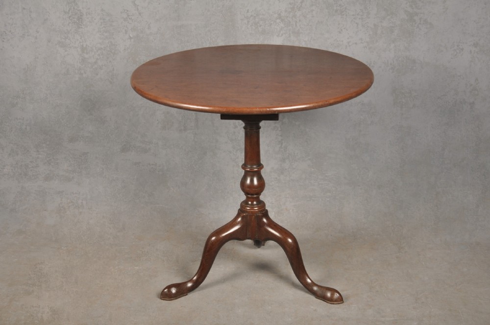 An 18th-century mahogany tripod table featuring a circular top, a central turned baluster pedestal, and three cabriole legs terminating in pad feet.
