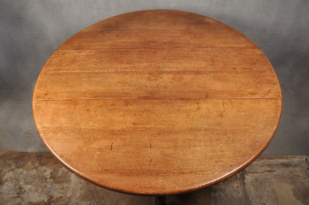 A large 18th-century oak gateleg table shown with one semi-circular drop leaf folded down and turned legs resting on rectangular stretchers. View III