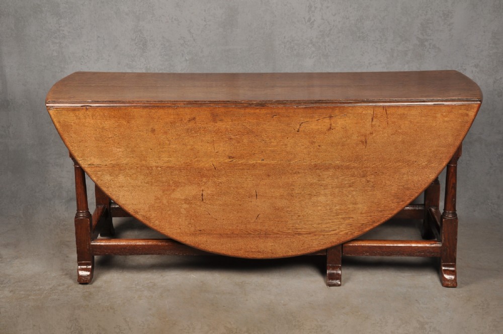A large 18th-century oak gateleg table shown with one semi-circular drop leaf folded down and turned legs resting on rectangular stretchers. View IV