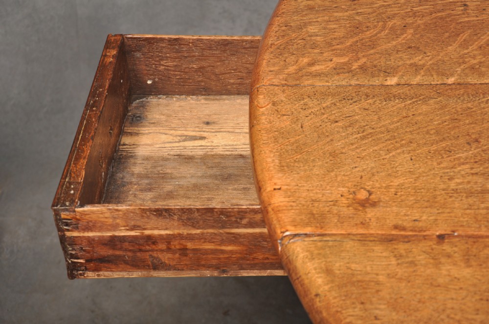 A large 18th-century oak gateleg table shown with one semi-circular drop leaf folded down and turned legs resting on rectangular stretchers. View V