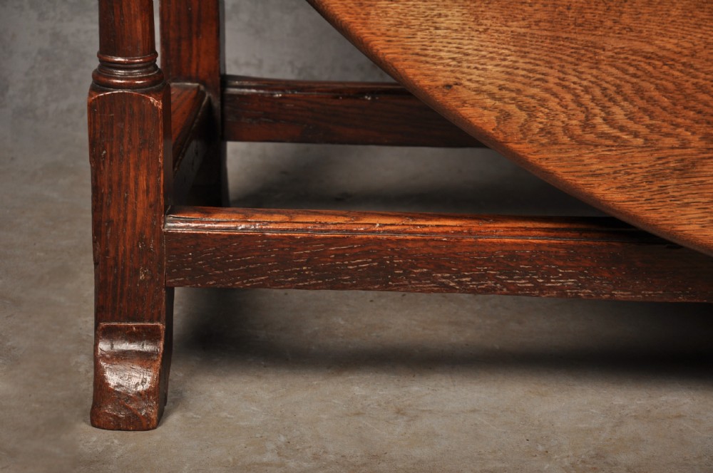 A large 18th-century oak gateleg table shown with one semi-circular drop leaf folded down and turned legs resting on rectangular stretchers. View VI