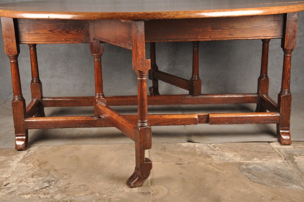 A large 18th-century oak gateleg table shown with one semi-circular drop leaf folded down and turned legs resting on rectangular stretchers. View VIII