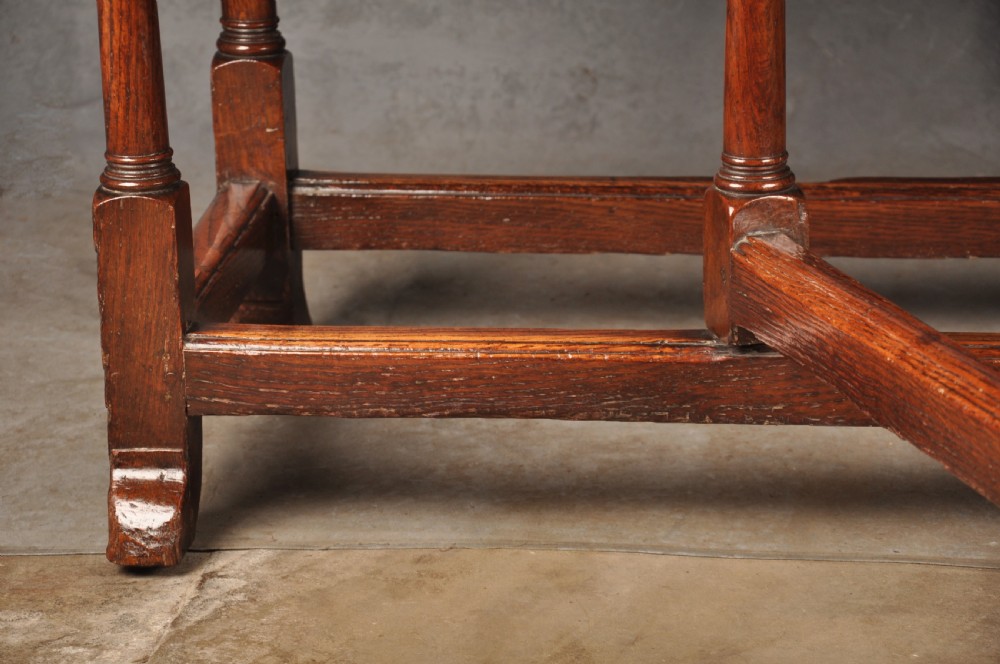 A large 18th-century oak gateleg table shown with one semi-circular drop leaf folded down and turned legs resting on rectangular stretchers. View IX