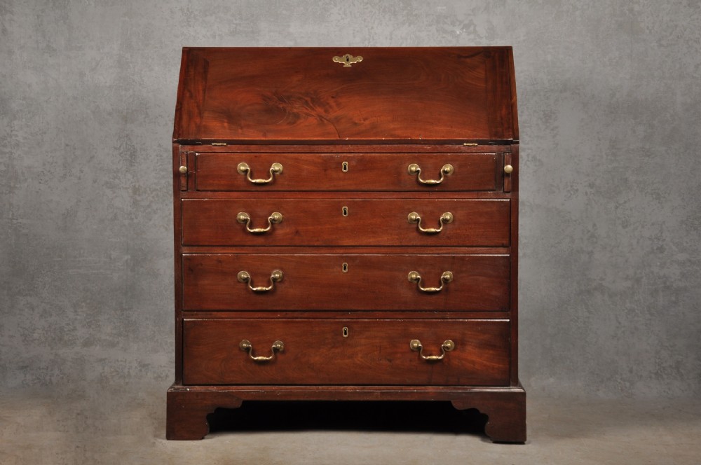 An eighteenth-century mahogany slant-front writing bureau featuring four graduated drawers with brass swan-neck handles and bracket feet.