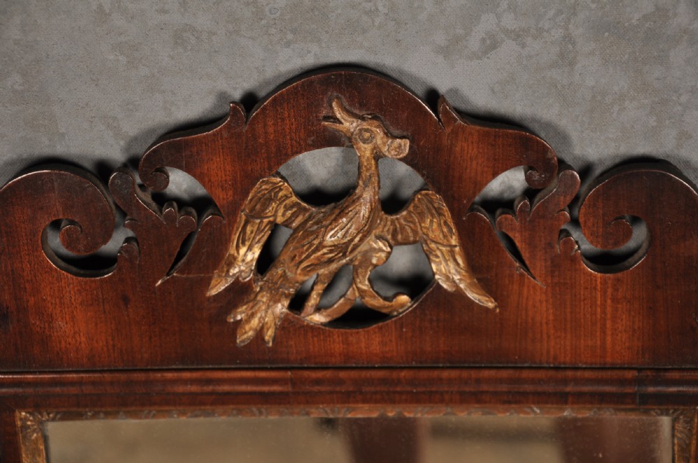 An 18th-century Chippendale mahogany wall mirror featuring a scrollwork fretwork frame, an inner gilt slip, and a carved gilt phoenix motif atop the cresting. View III