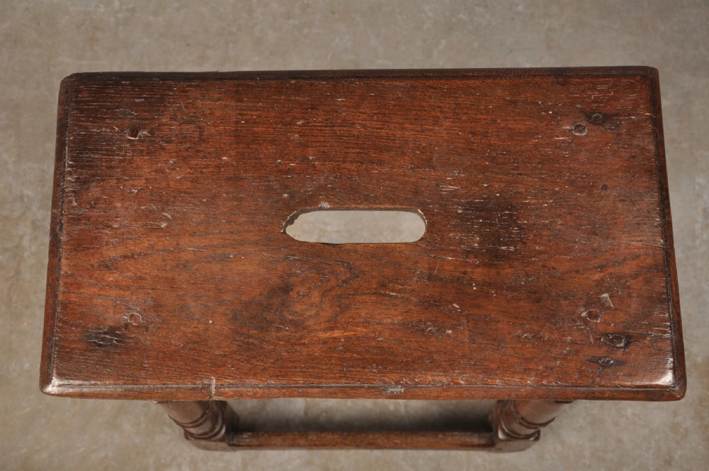 A 17th-century oak joint stool with turned legs, mortise-and-tenon peg construction, and lower perimeter stretchers. View III