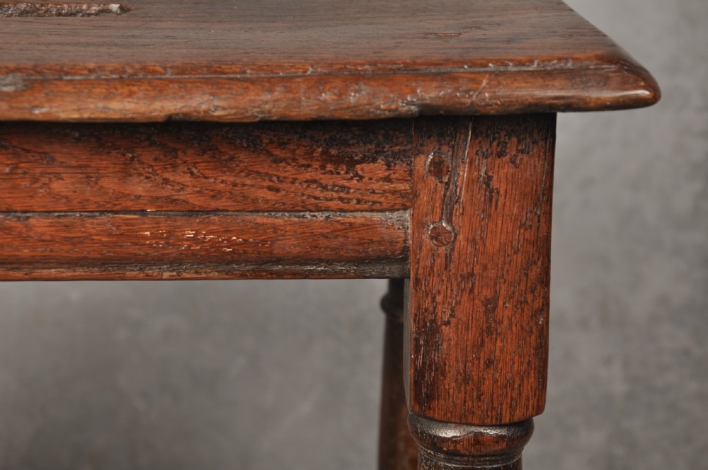 A 17th-century oak joint stool with turned legs, mortise-and-tenon peg construction, and lower perimeter stretchers. View V