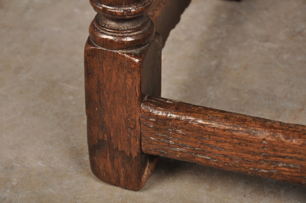 A 17th-century oak joint stool with turned legs, mortise-and-tenon peg construction, and lower perimeter stretchers. View VI