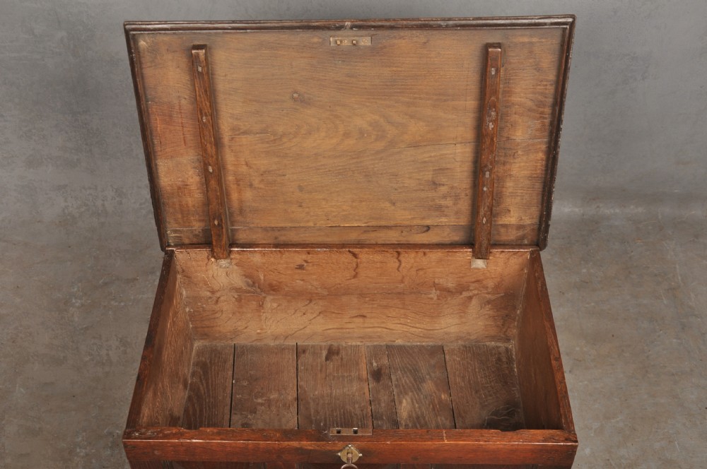 An 18th-century dark oak coffer bach with a hinged lid, three front panels, two lower drawers, and brass handles. View IV