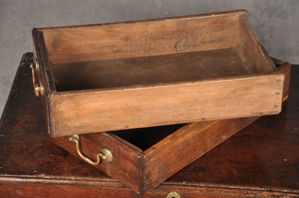 An 18th-century dark oak coffer bach with a hinged lid, three front panels, two lower drawers, and brass handles. View VIII