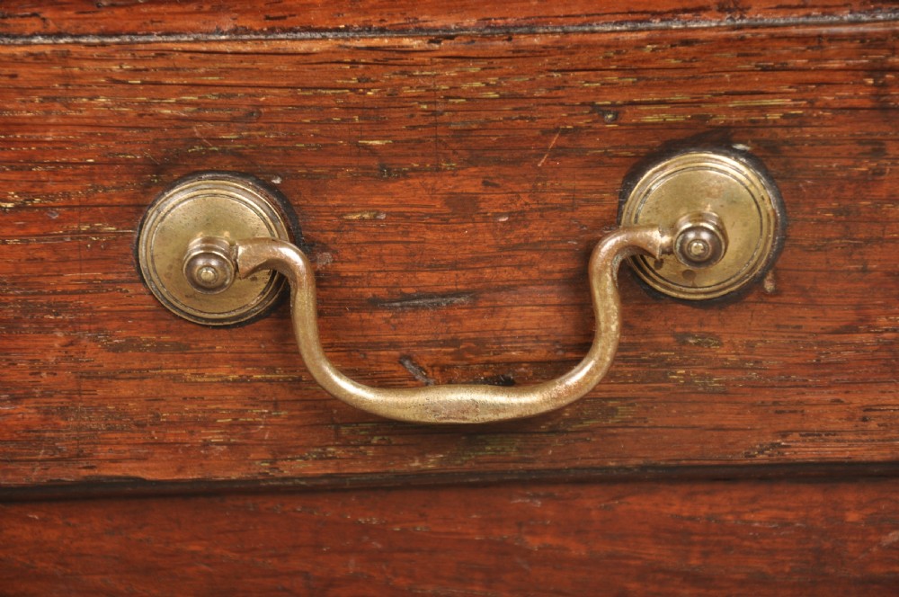 An 18th-century dark oak coffer bach with a hinged lid, three front panels, two lower drawers, and brass handles. View IX