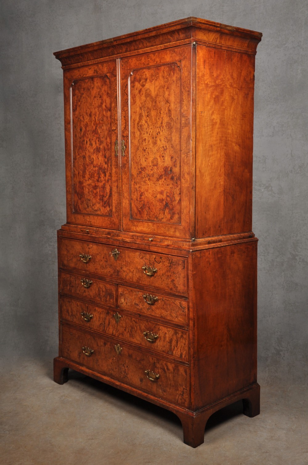 An early eighteenth-century burr walnut secretaire cabinet featuring double upper doors and a lower chest of drawers with brass handles. View III